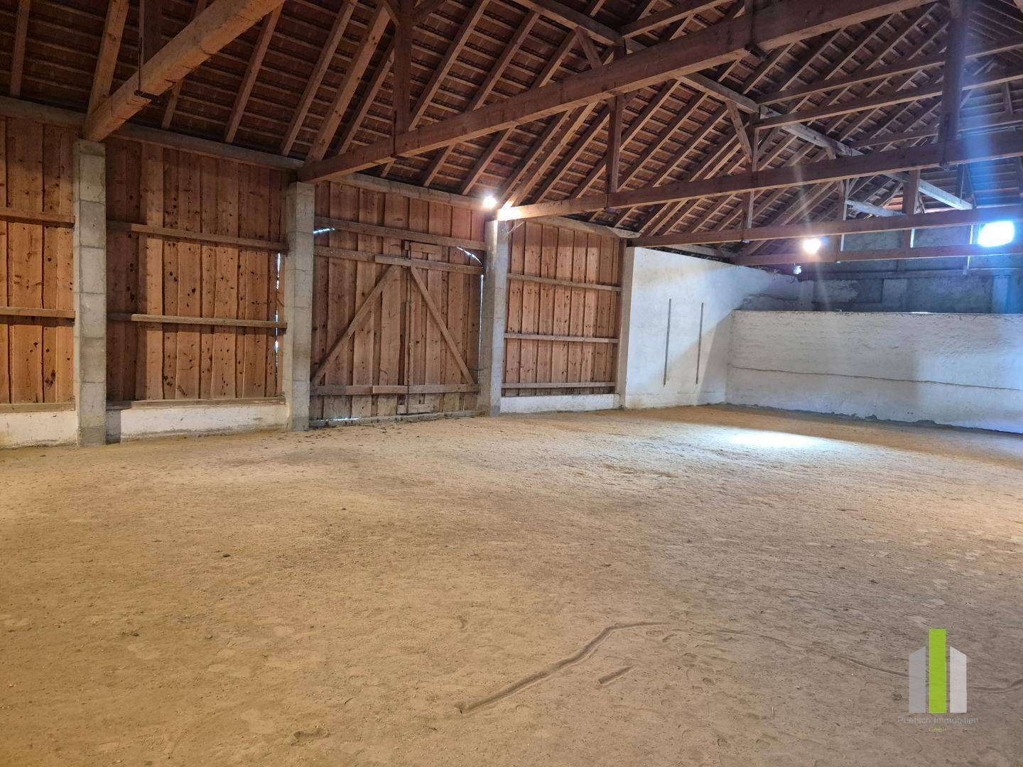 Geräumige Scheune mit Holzbalkenkonstruktion und Sandboden, vielseitig nutzbar.