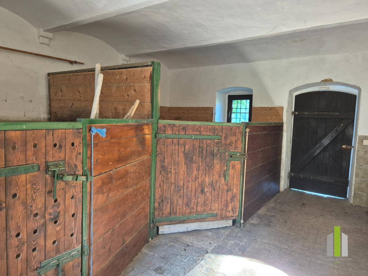 Innenansicht eines Stalls mit Holztrennwänden und gewölbter Decke, im Originalzustand.