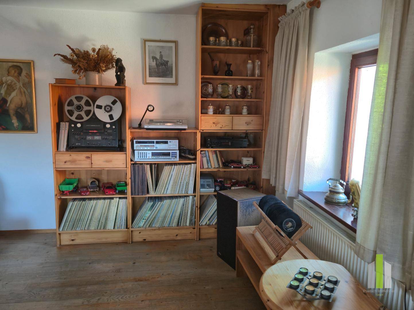 Raum mit Holzdielenboden, Regalen voller Schallplatten und einem Plattenspieler, ideal für Musikliebhaber.