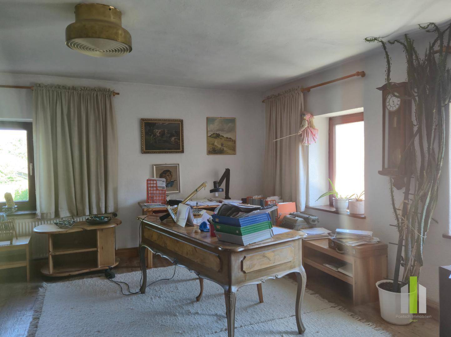 Arbeitszimmer mit Holzdielenboden, großem Schreibtisch und Blick ins Grüne, ideal für Homeoffice.