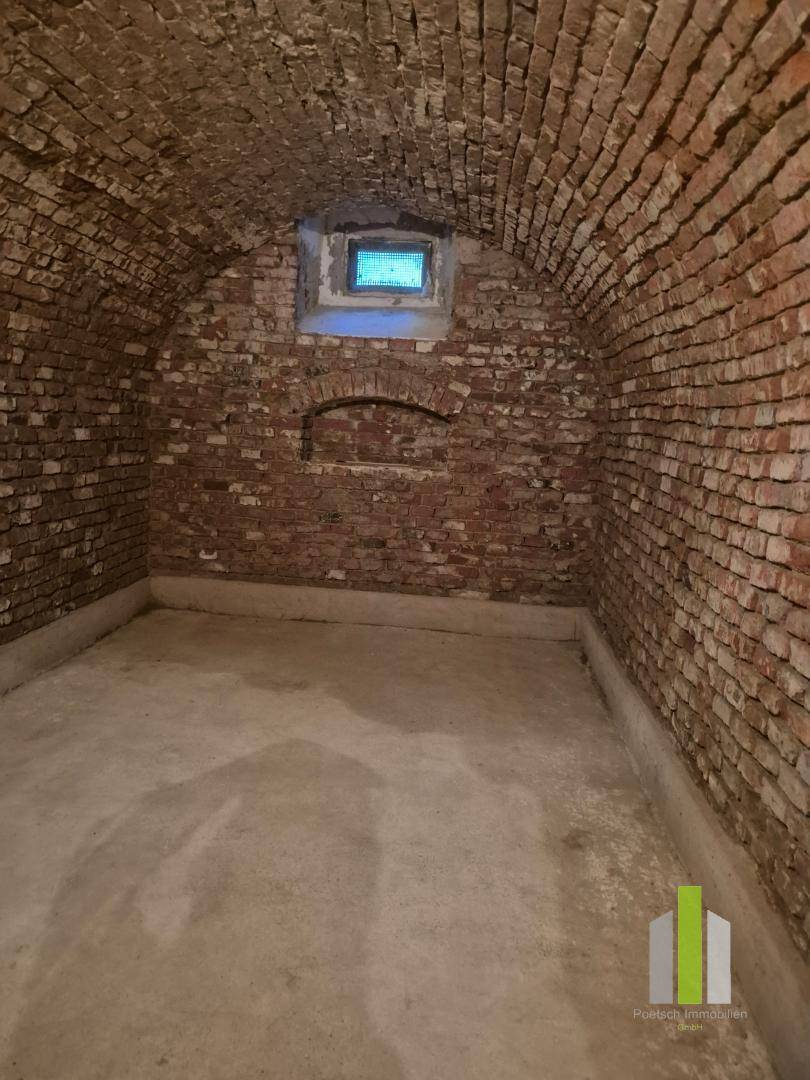Gewölbekeller mit Ziegelwänden, Betonboden und einem kleinen Fenster, gut erhalten.