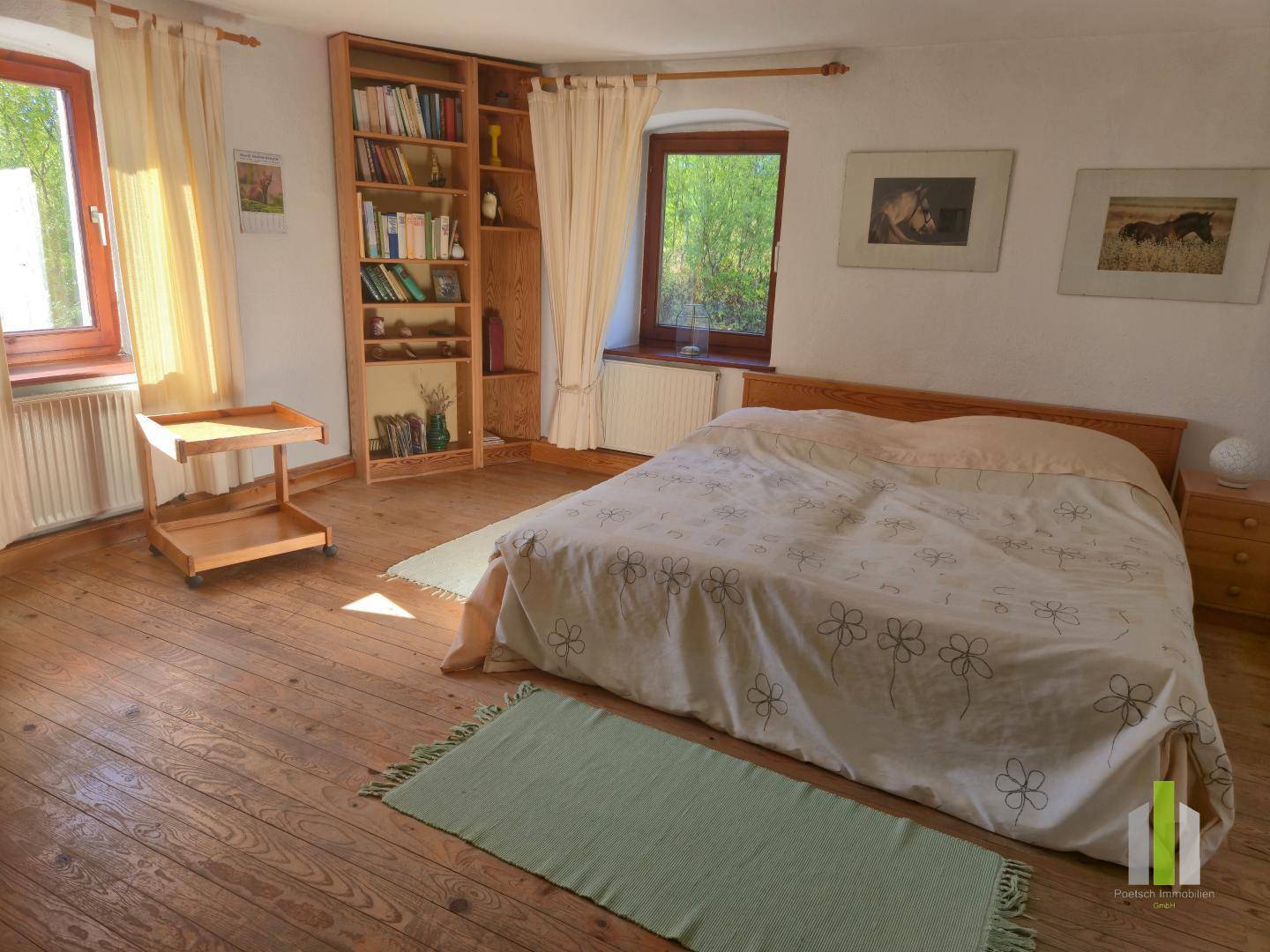 Geräumiges Schlafzimmer mit Doppelbett, Holzboden und Bücherregal.