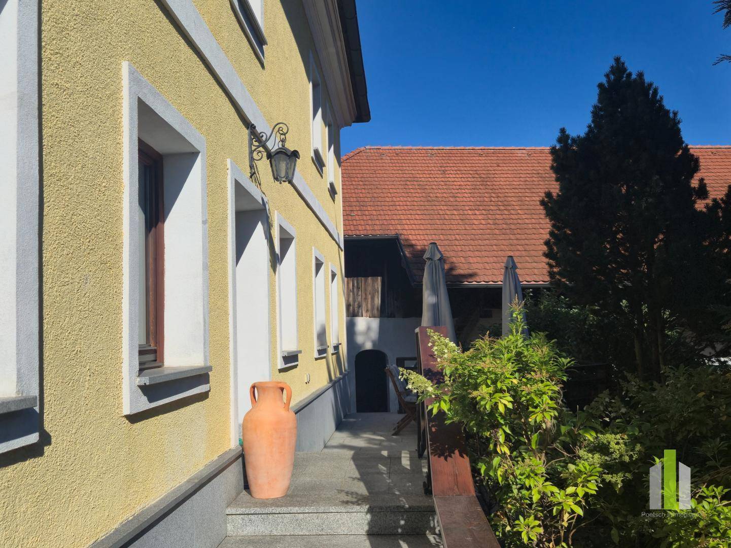Seitenansicht des Hauses mit einem Weg, der zum überdachten Außenbereich führt. 