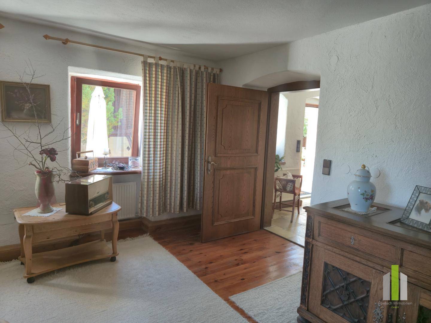 Heller Flur mit Holzboden, traditionellen Möbeln und Blick in einen weiteren Raum.