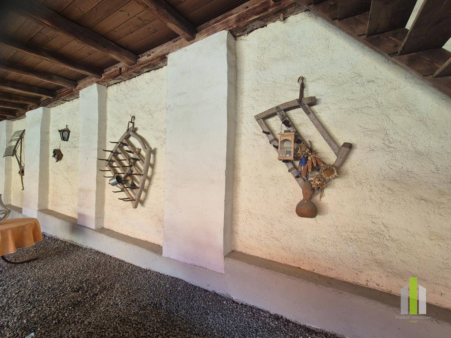Detailansicht einer Wand im überdachten Bereich mit rustikalen Dekorationen und Weinregal. 