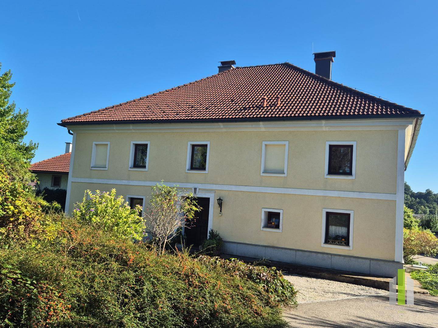 Charmantes gelbes Haus mit rotem Ziegeldach und traditioneller Architektur unter strahlend blauem Himmel. 