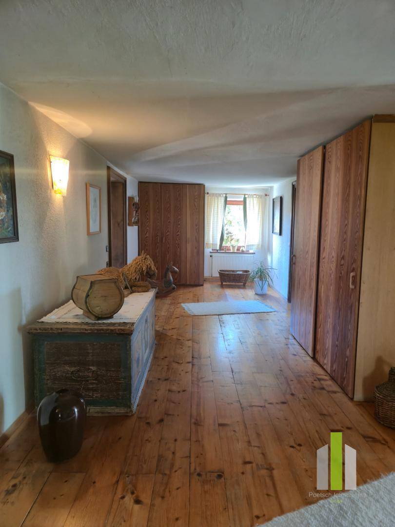 Langer Flur mit Holzdielenboden, Holzschränken und einer Truhe, gut beleuchtet.