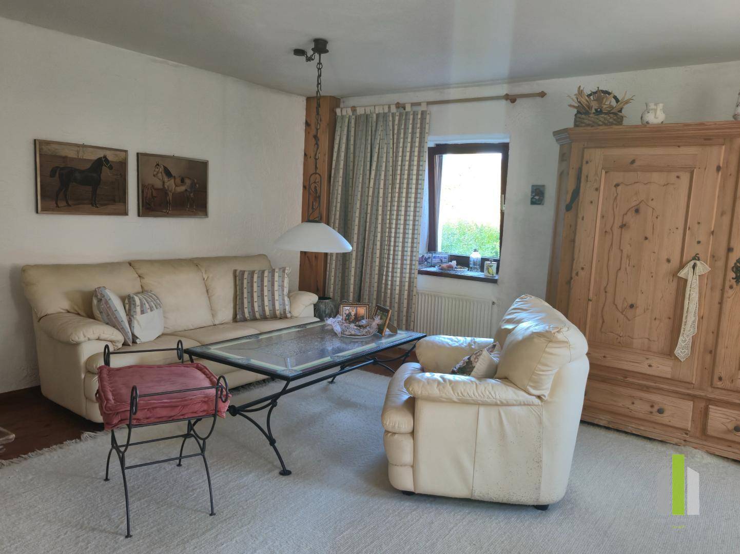 Gemütliches Wohnzimmer mit beigem Sofa, Holzboden und traditionellem Holzschrank.