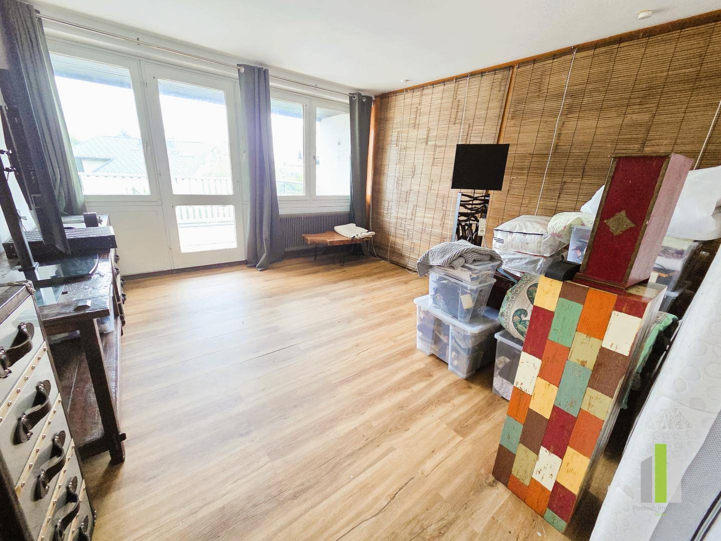 Zimmer mit Laminatboden, großen Fenstern und Zugang zu einem Außenbereich.