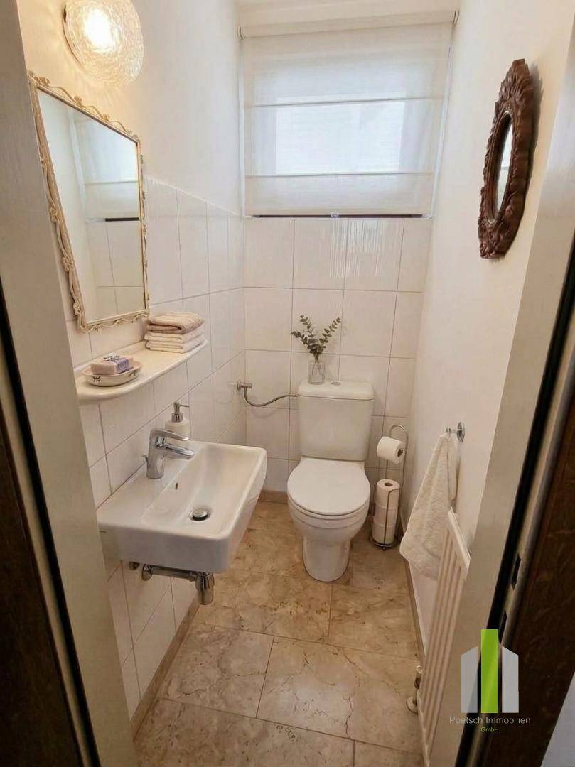 Kleines Gäste-WC mit Fliesenboden, Waschbecken und wandmontierter Toilette.