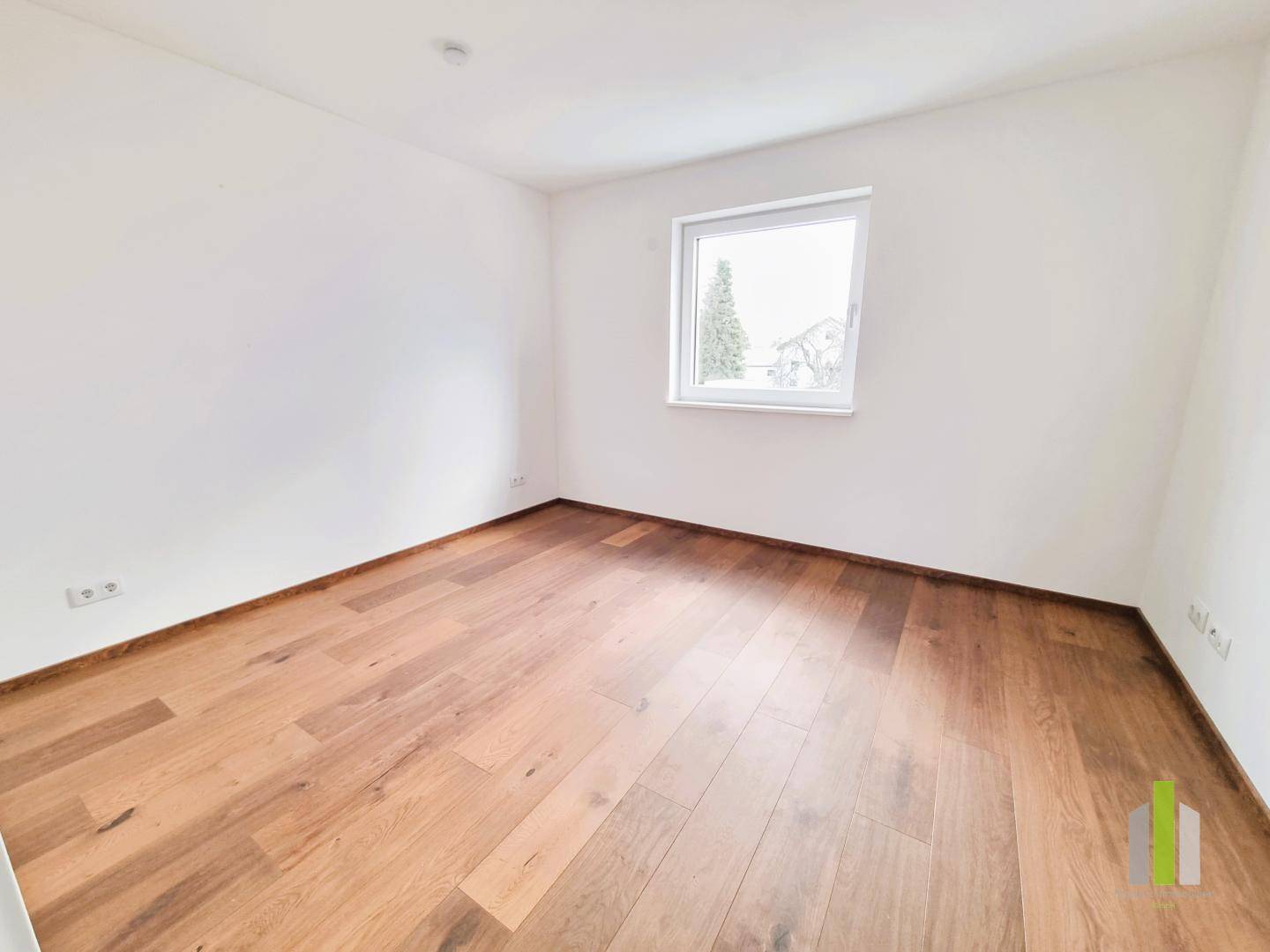 Leeres Schlafzimmer mit Holzboden und einem Fenster, bereit zur individuellen Einrichtung.