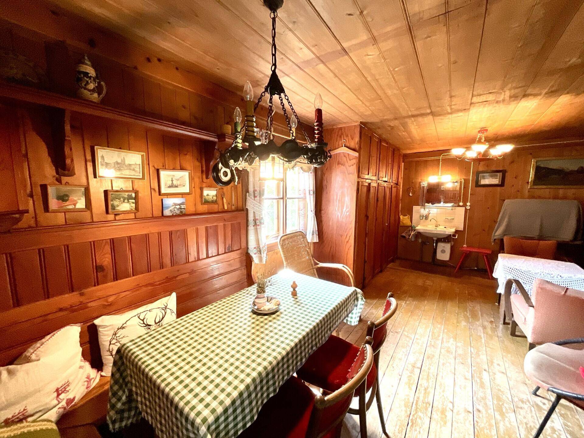Traditioneller Essbereich mit Holzvertäfelung, karierter Tischdecke und rustikalem Kronleuchter.