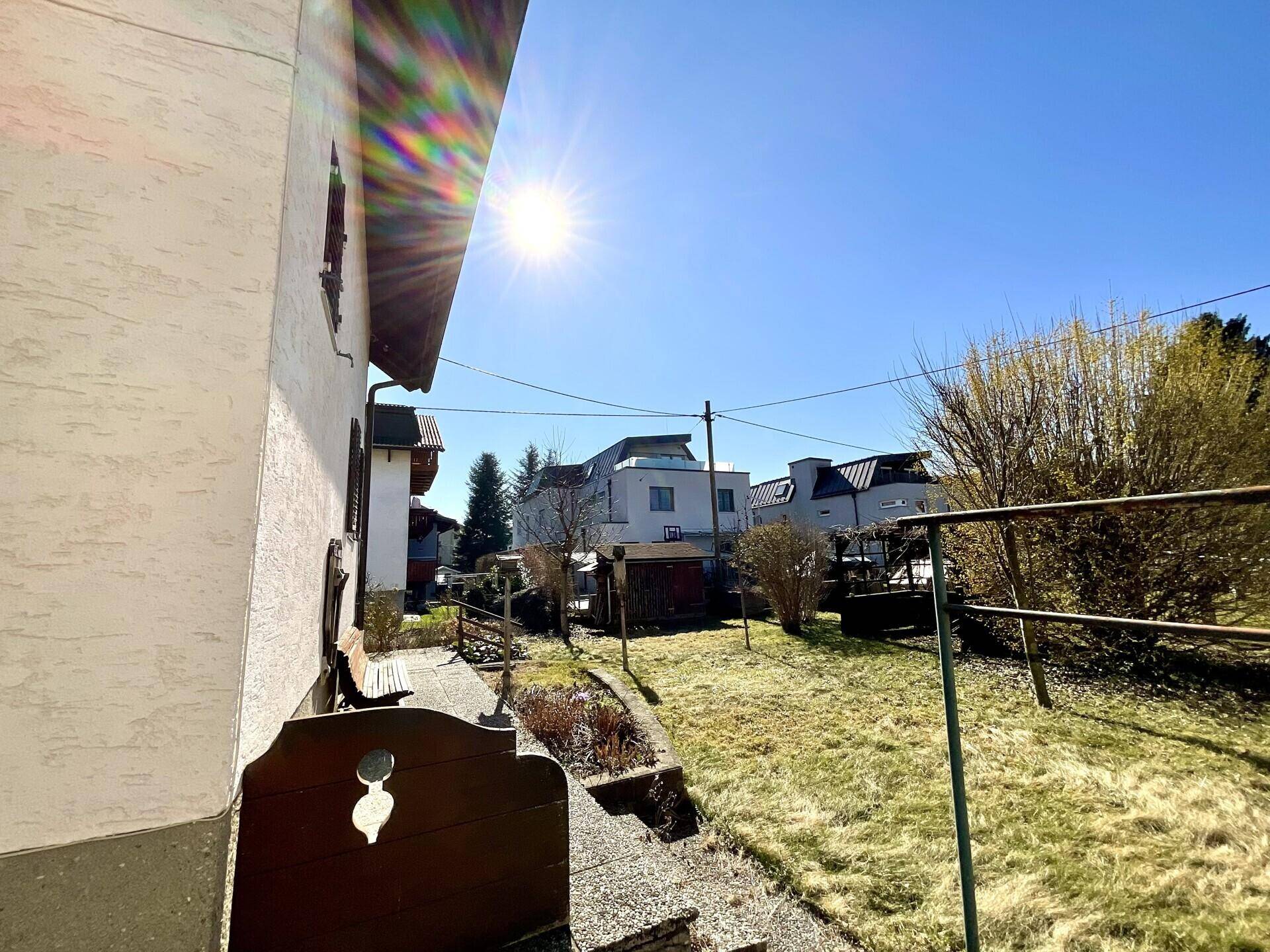 Sonniger Außenbereich mit Rasenfläche und Blick auf benachbarte Gebäude.