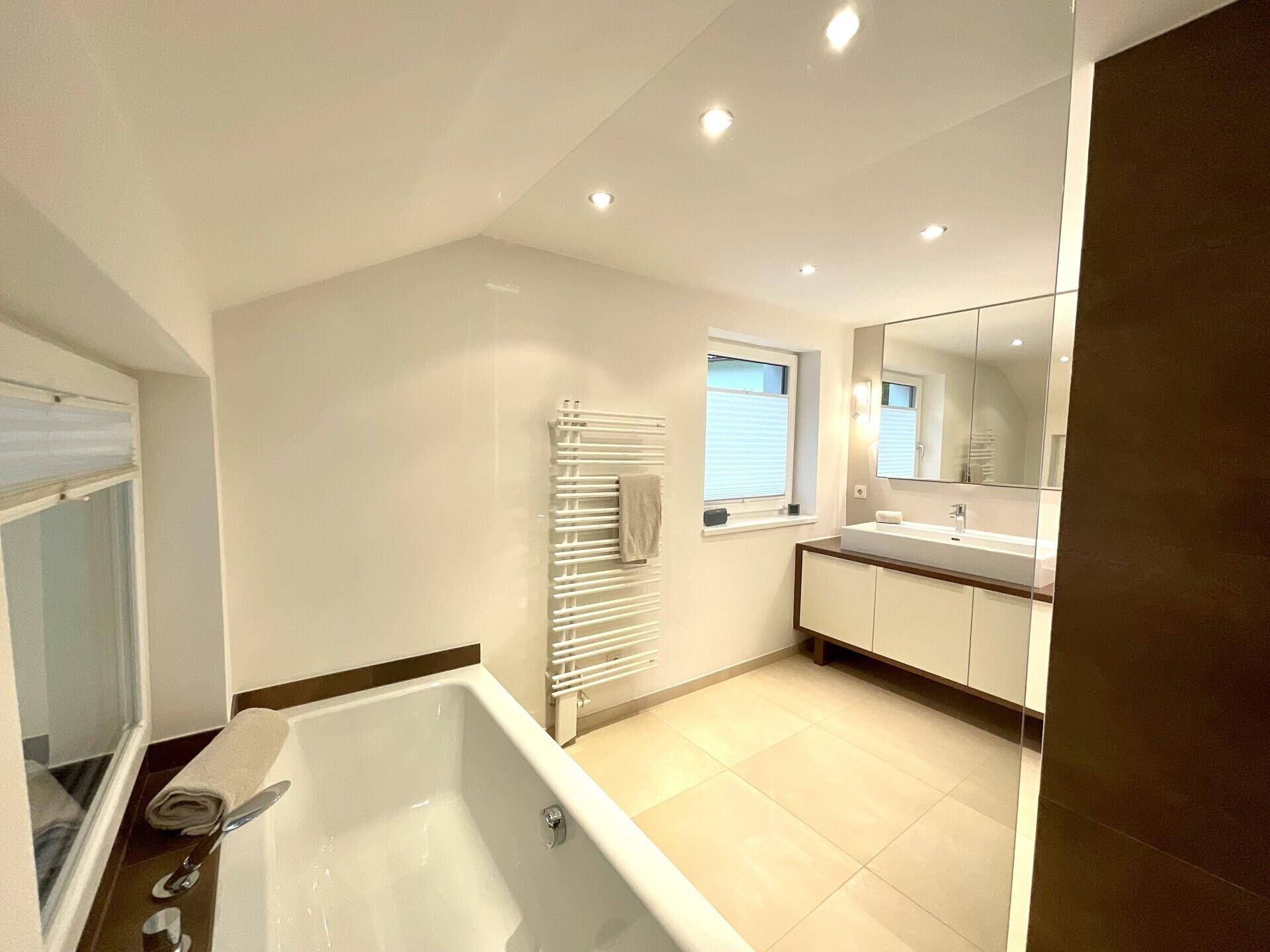 Geräumiges Badezimmer mit Badewanne, modernem Waschtisch und großer Dusche, hell und funktional.