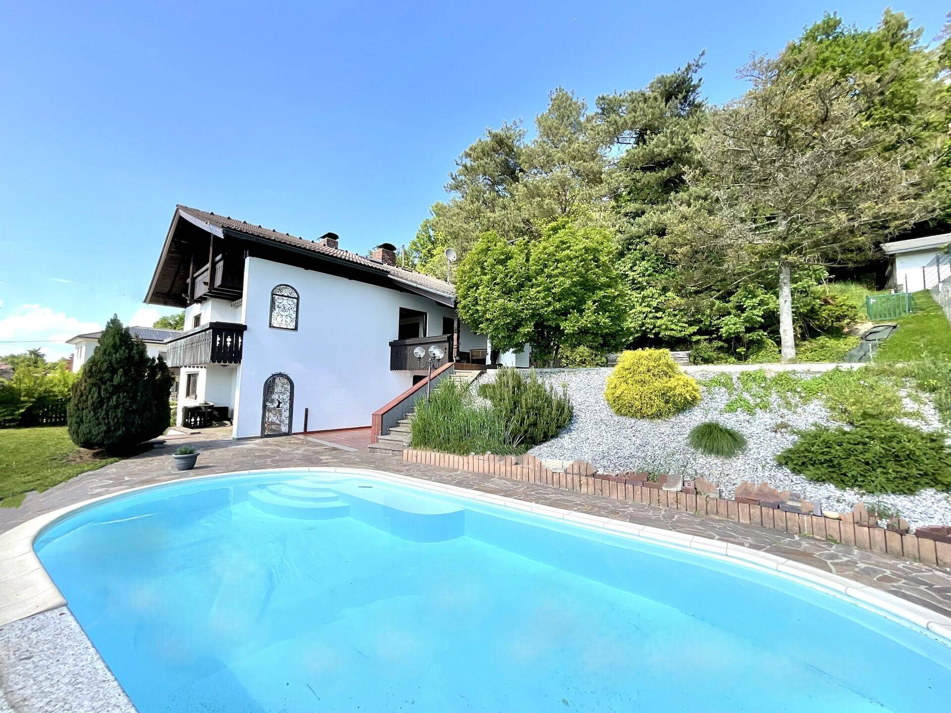 Großzügiger Außenbereich mit erfrischendem Pool und Blick auf das charmante Haus im Grünen.