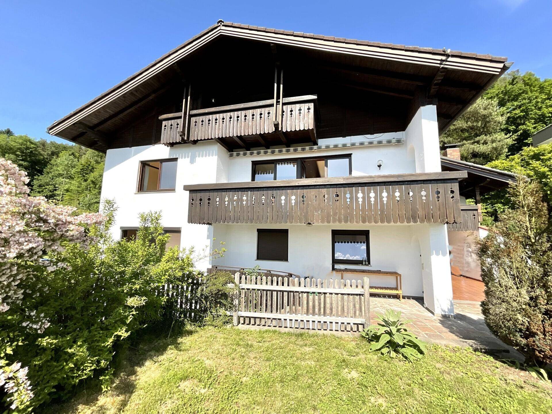 Traditionelles Haus mit Holzbalkonen und gepflegter Fassade, umgeben von üppigem Grün.