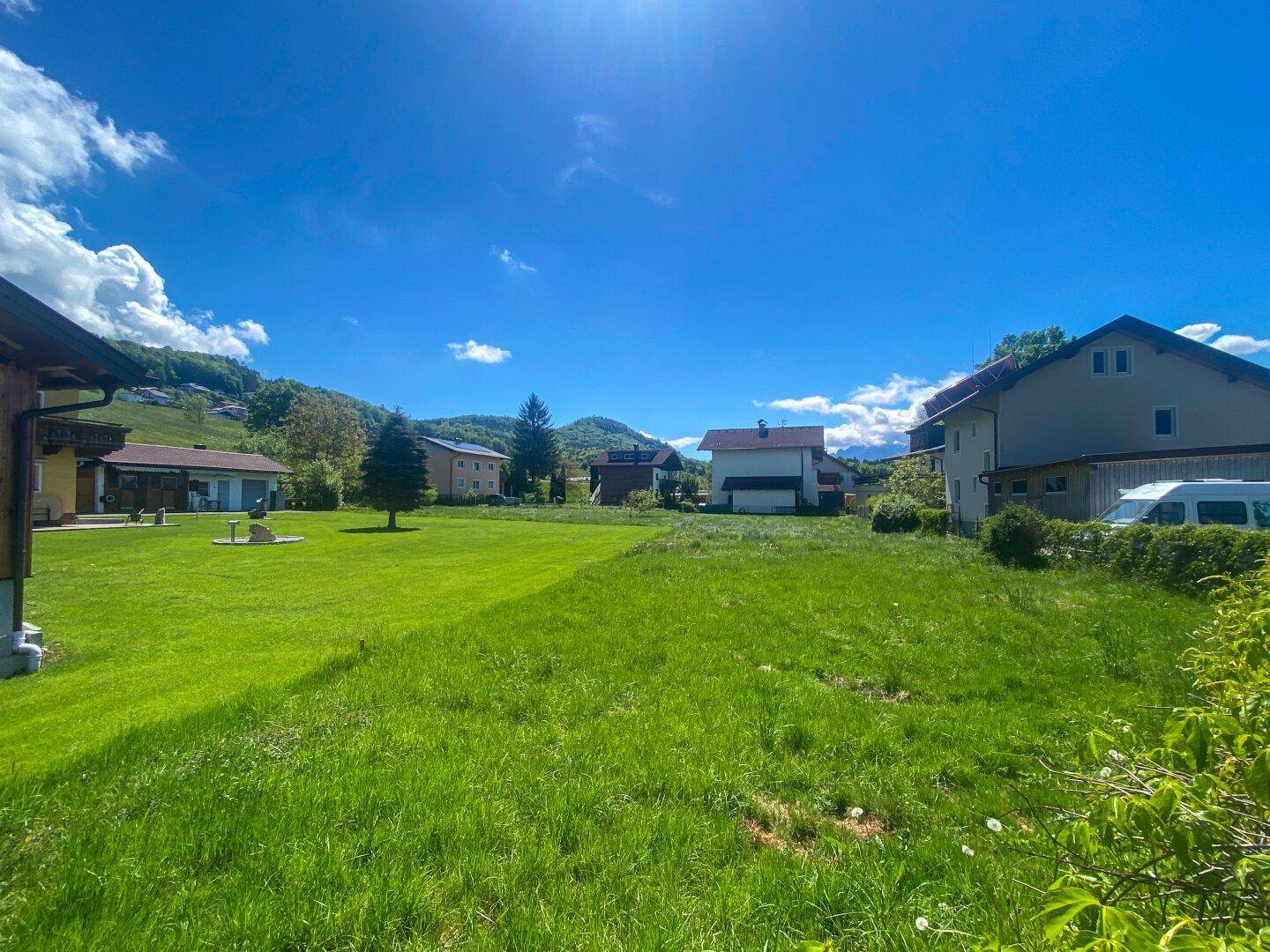 Sonnige Grünfläche mit Blick auf die umliegende Bebauung und Berglandschaft.
