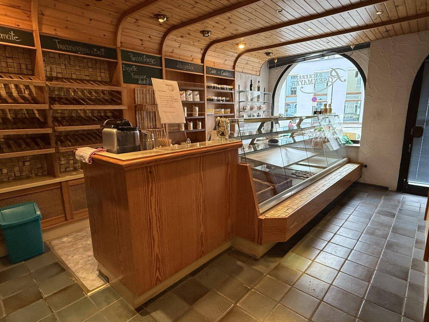 Gemütlicher Bäckereiladen mit Holzvertäfelung, Verkaufstheke und Auslagen für Backwaren.