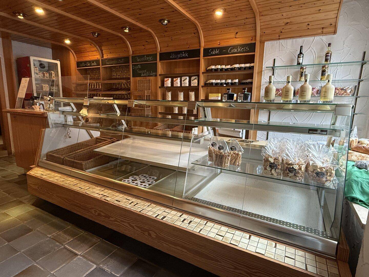 Verkaufstheke in der Bäckerei mit Glasvitrinen und Holzverkleidung zur Präsentation der Produkte.