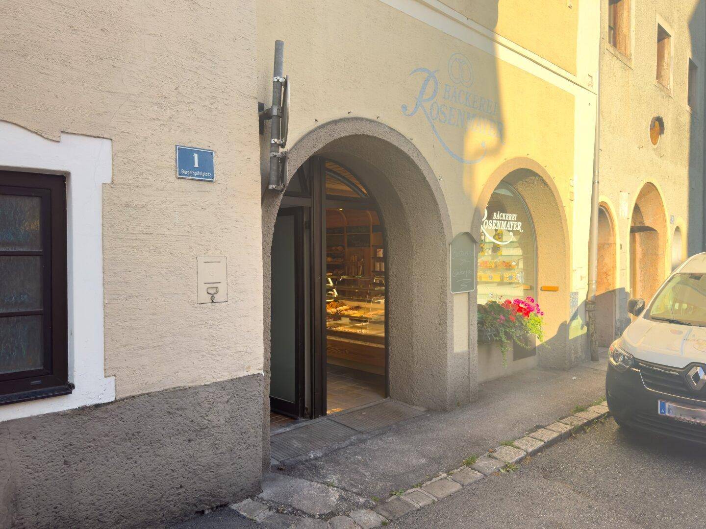 Eingangsbereich der Bäckerei mit gewölbtem Tor und Schaufenster in einer historischen Gasse.