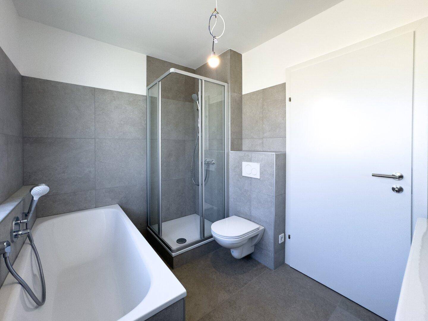 Geräumiges Badezimmer mit Badewanne, Duschkabine und wandhängendem WC in modernem Design.
