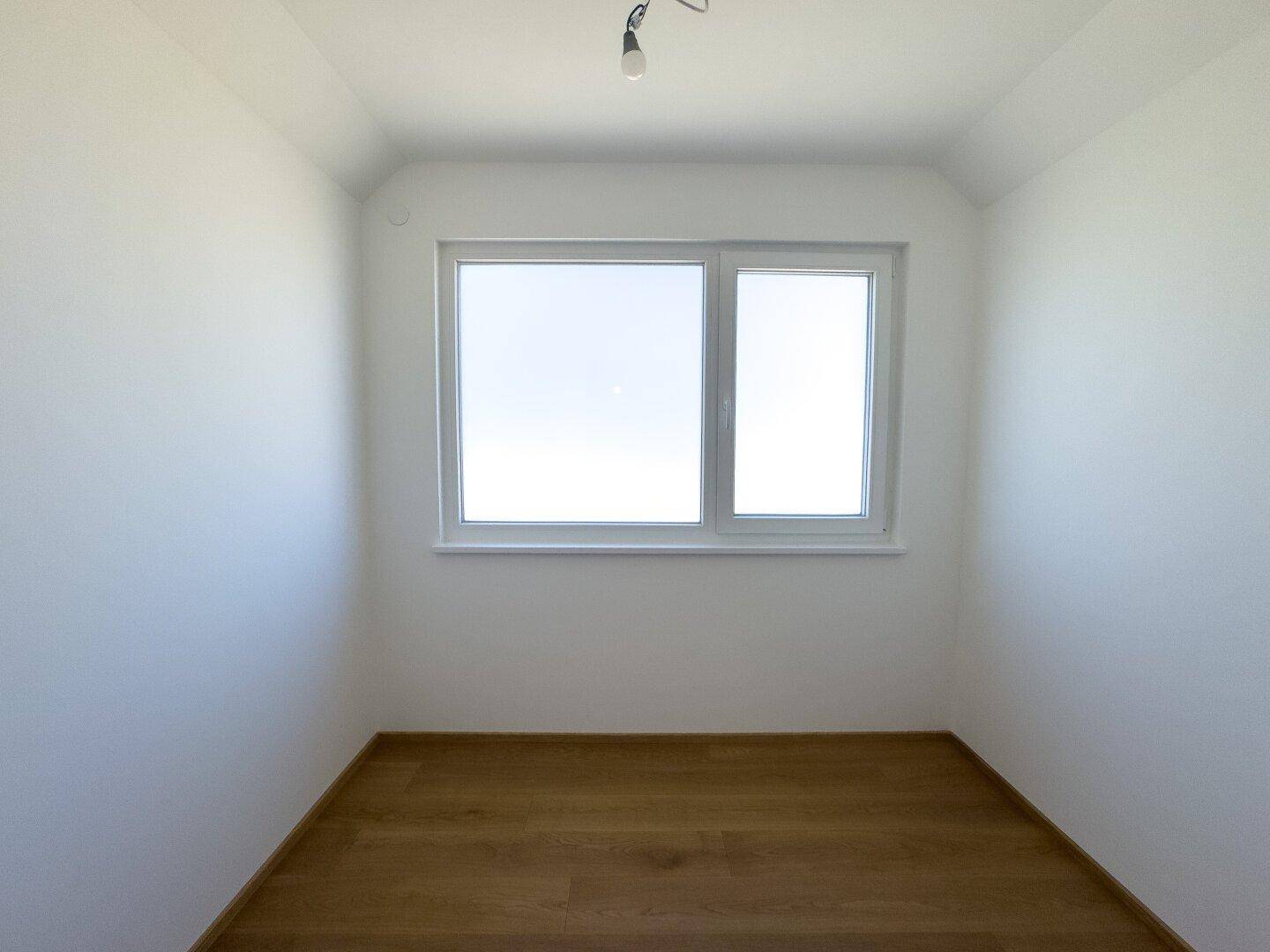 Kleines, helles Zimmer mit Holzboden und Fenster, ideal als Kinder- oder Arbeitszimmer.