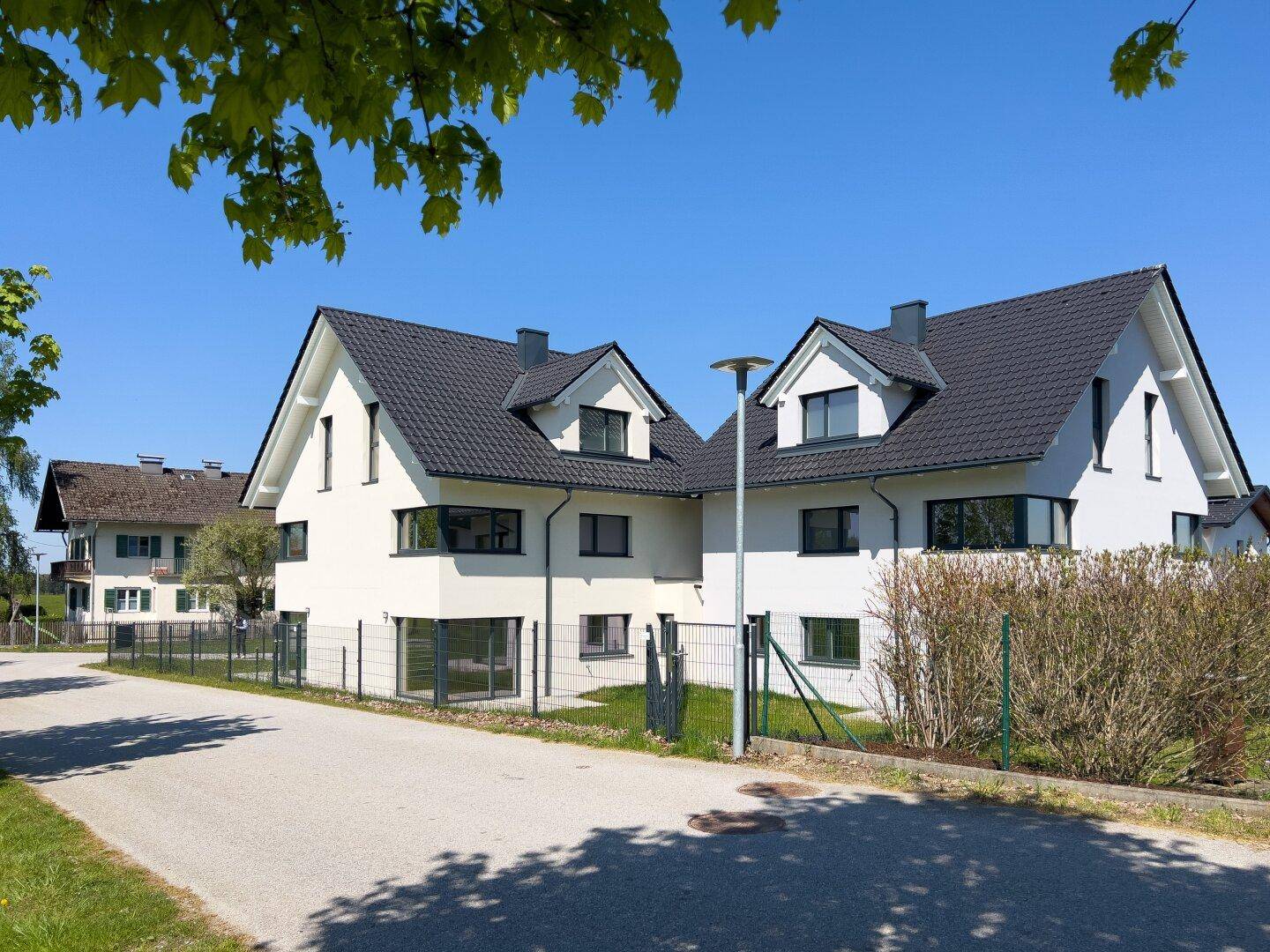 Ansicht der modernen Doppelhaushälften von der Straße aus mit gepflegter Umgebung.