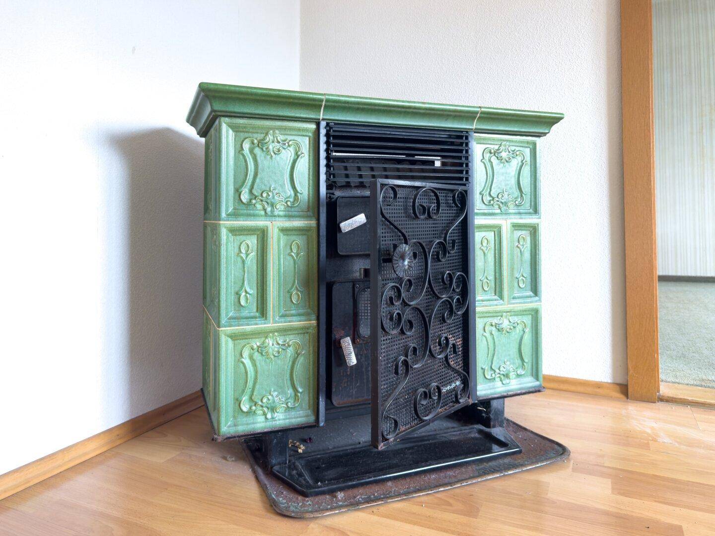 Grüner Kachelofen mit kunstvollen Verzierungen, ein traditionelles Heizelement im Wohnbereich.