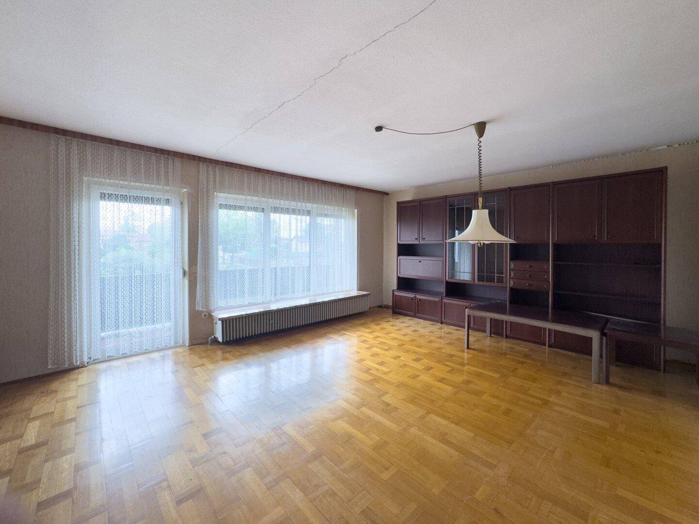 Geräumiges Wohnzimmer mit Parkettboden und großer Schrankwand, bereit zur Neugestaltung.