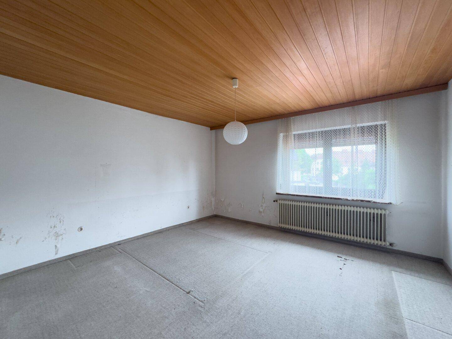 Geräumiges Zimmer mit Holzdecke und Teppichboden, ideal für individuelle Einrichtung.