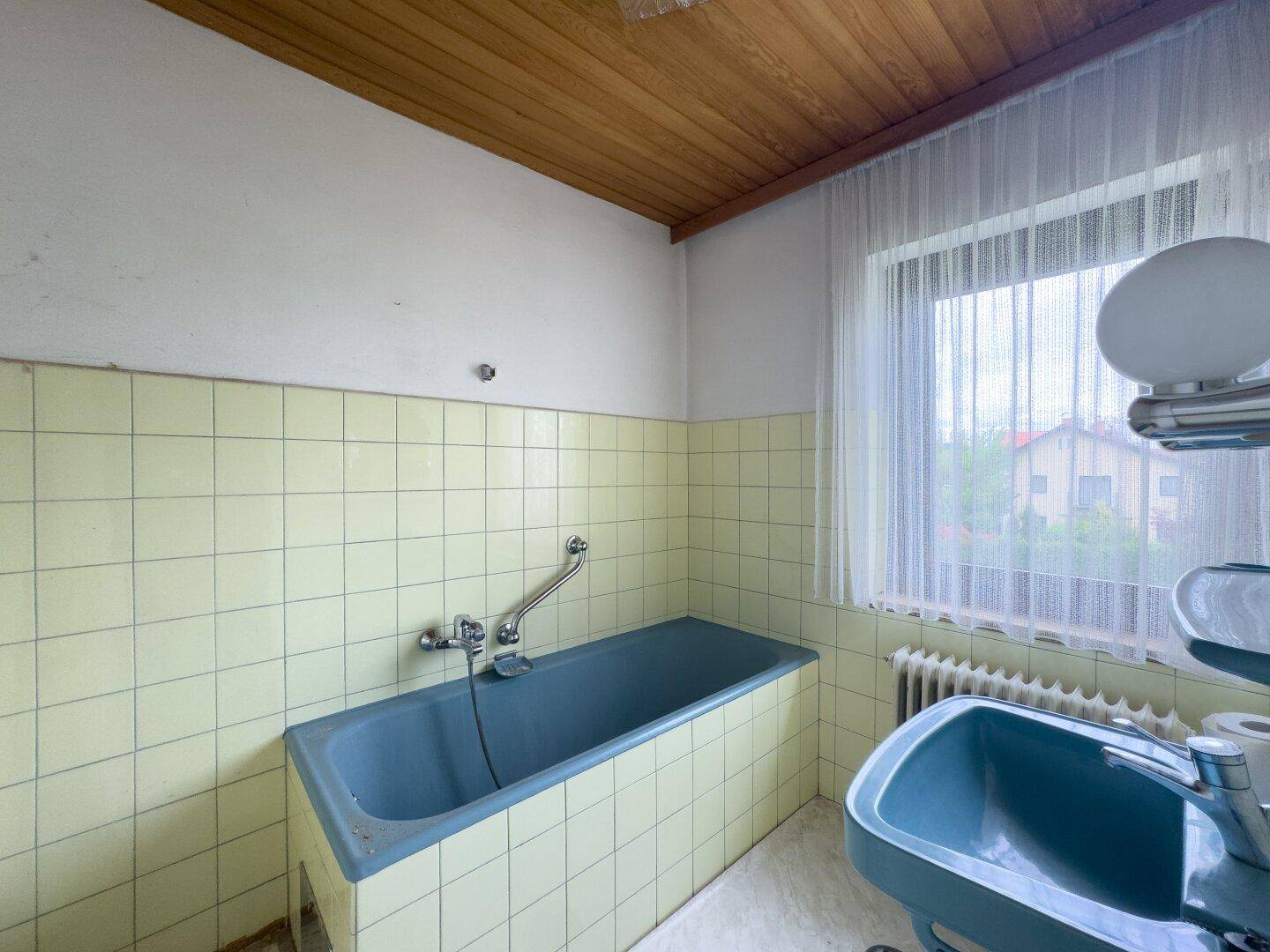 Badezimmer im Retro-Stil mit blauer Badewanne, gelben Fliesen und Holzdecke.