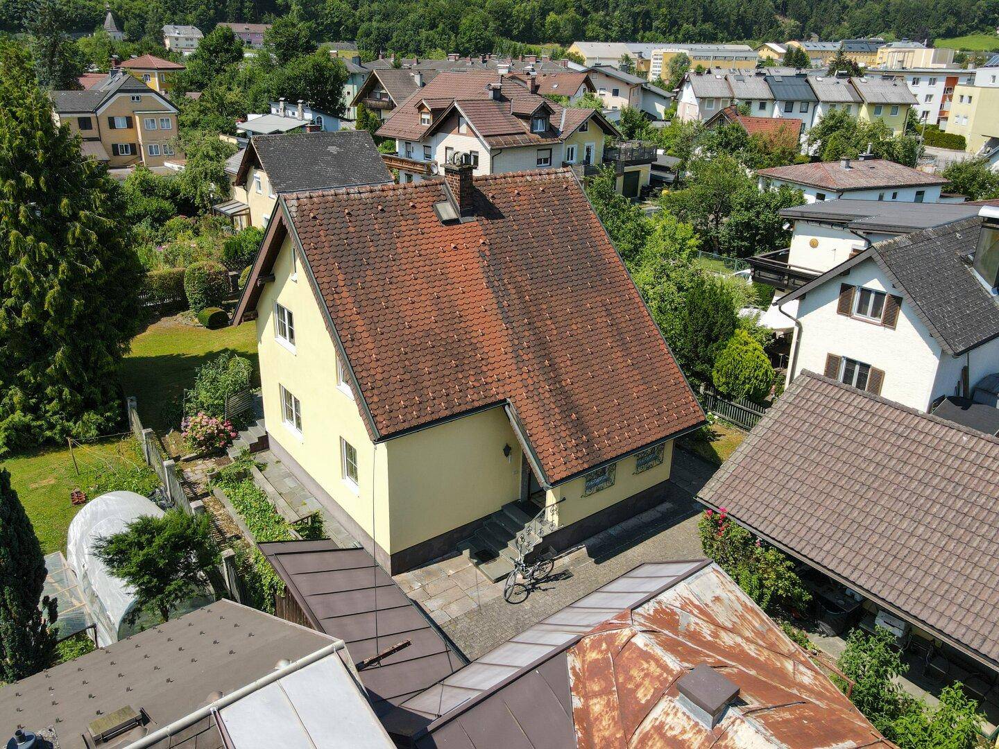 Luftaufnahme des Einfamilienhauses mit rotem Ziegeldach und umliegender Wohnsiedlung.