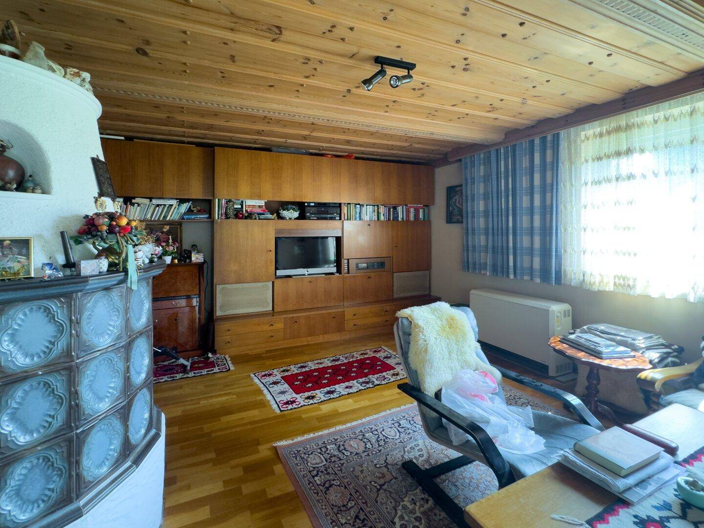 Gemütliches Wohnzimmer mit Holzbalkendecke, Kachelofen und traditionellen Holzmöbeln.