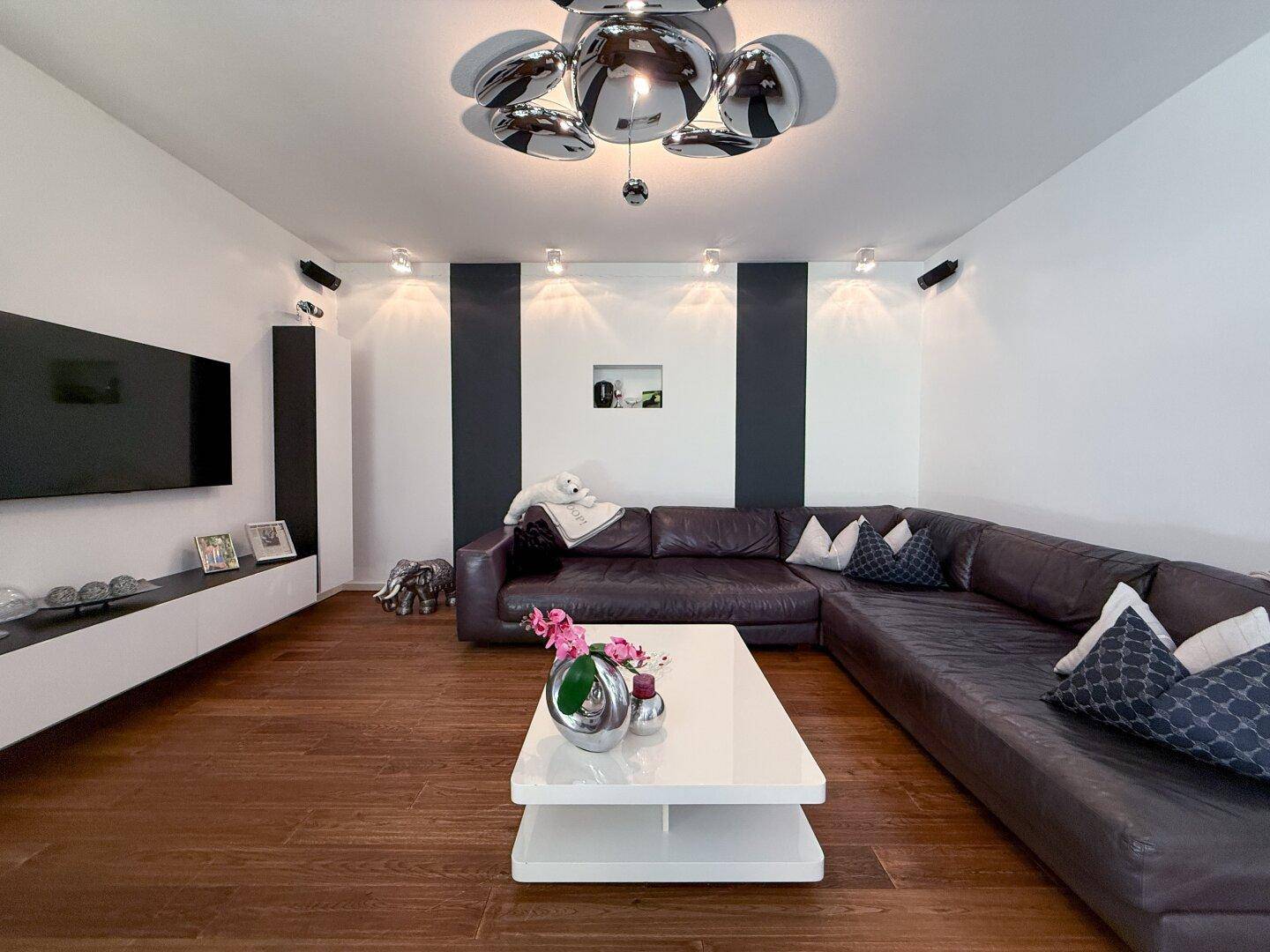 Stilvolles Wohnzimmer mit bequemer Ledercouch, elegantem Couchtisch und Akzentwänden in Schwarz-Weiß.