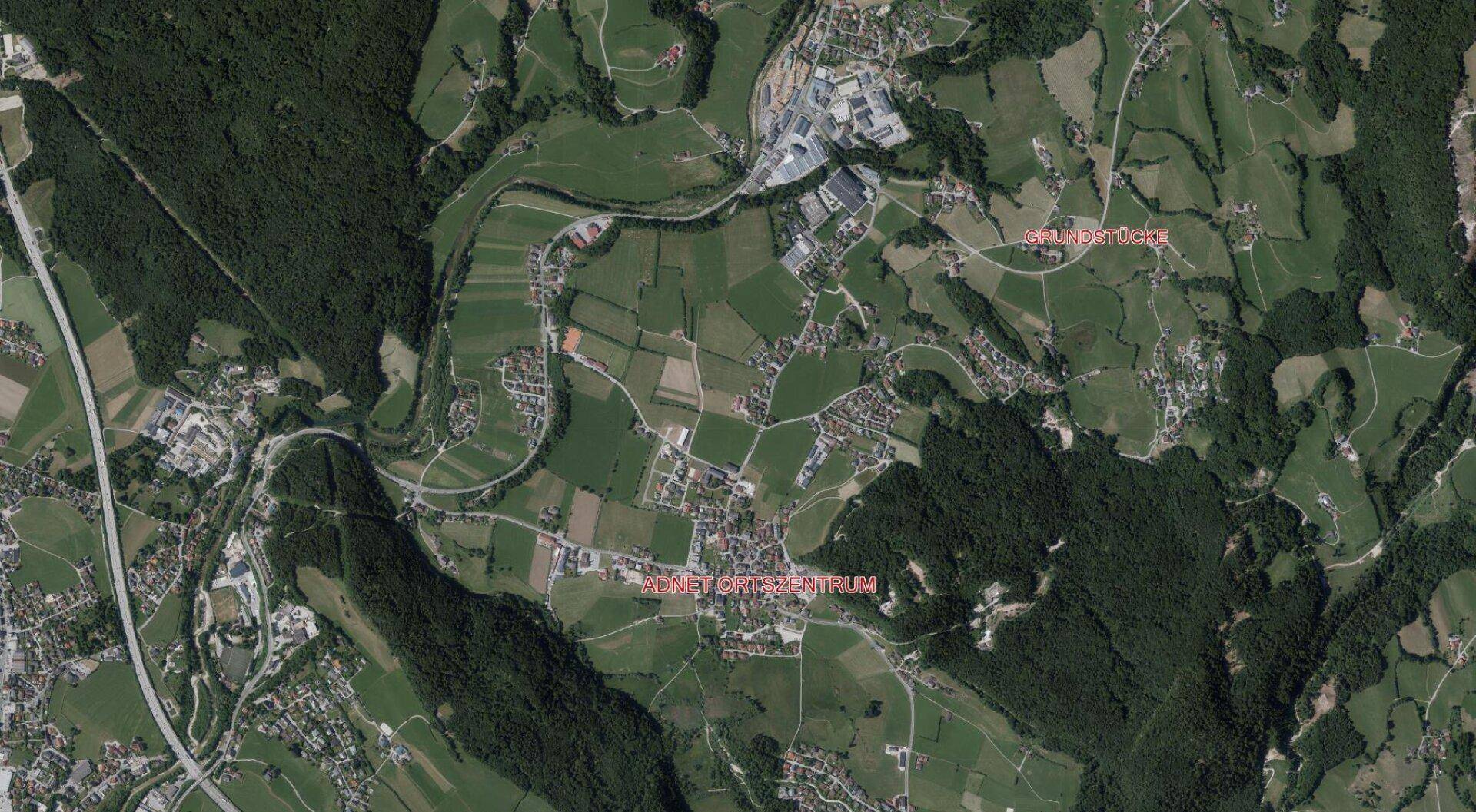 Luftaufnahme einer weitläufigen Landschaft mit grünen Feldern, Wäldern und Siedlungsgebieten.