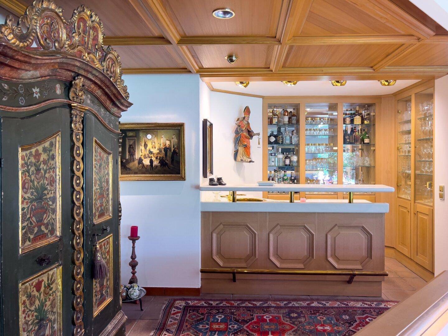 Traditionelle Hausbar mit Holzvertäfelung, Glasvitrinen und einem antiken Schrank im Wohnbereich.