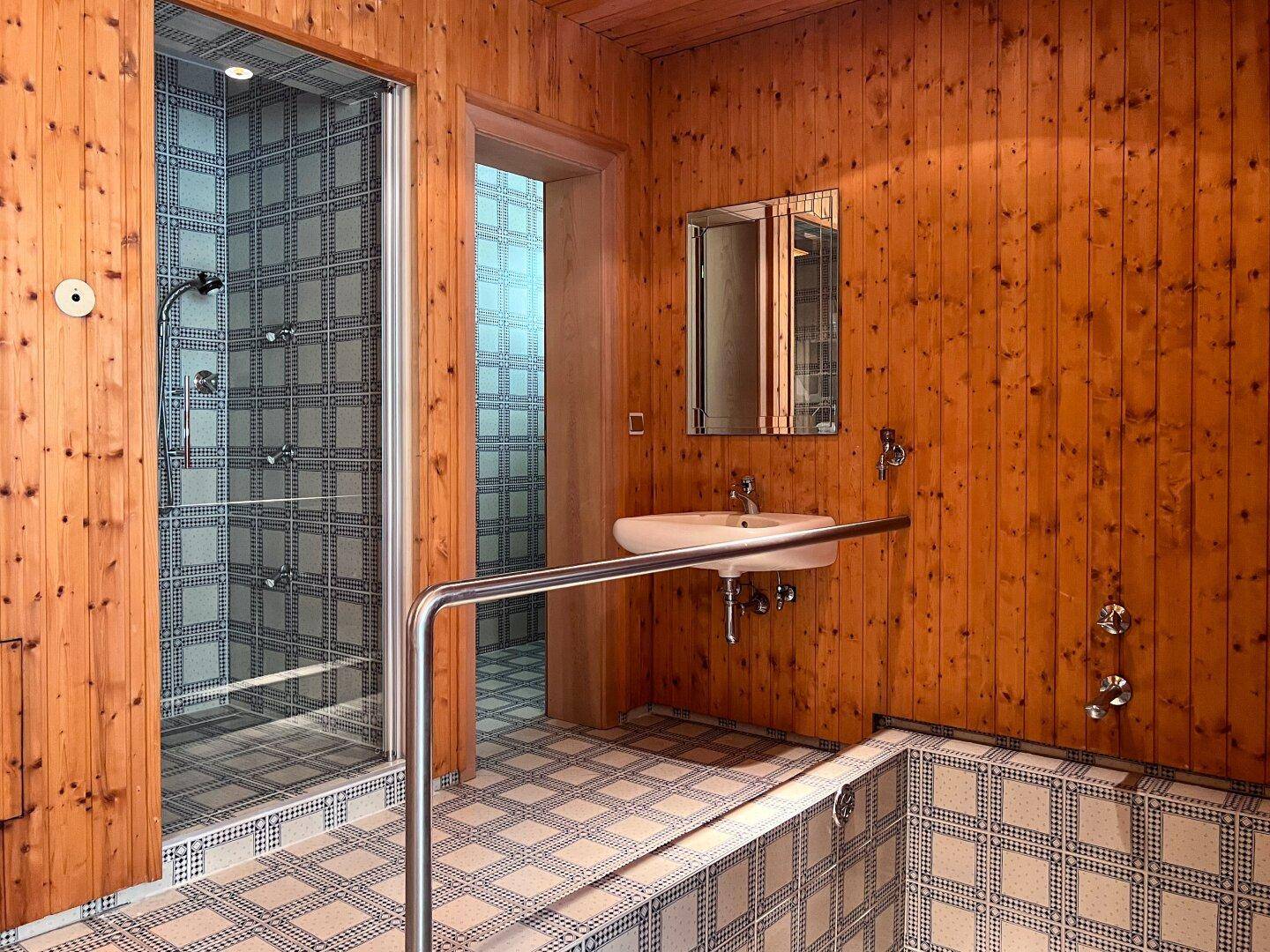 Badezimmer im alpinen Stil mit Holzvertäfelung, Duschkabine und gefliestem Boden.