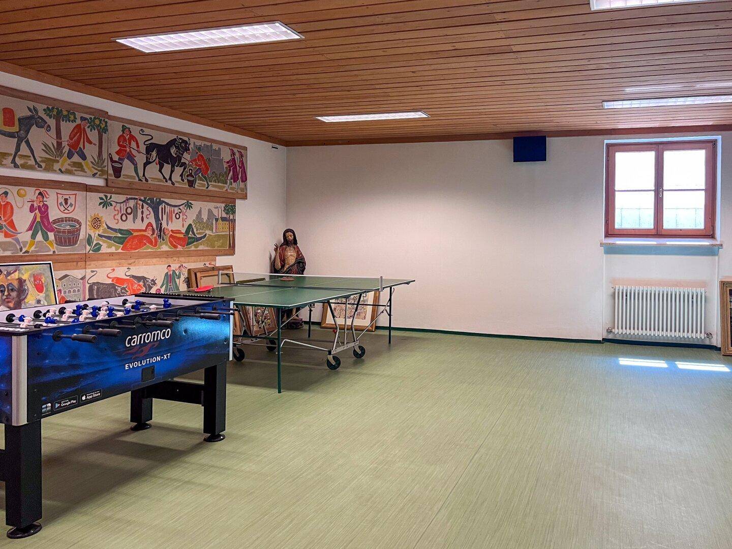 Großer Hobbyraum mit Tischfußball, Tischtennisplatte und Holzbalkendecke.