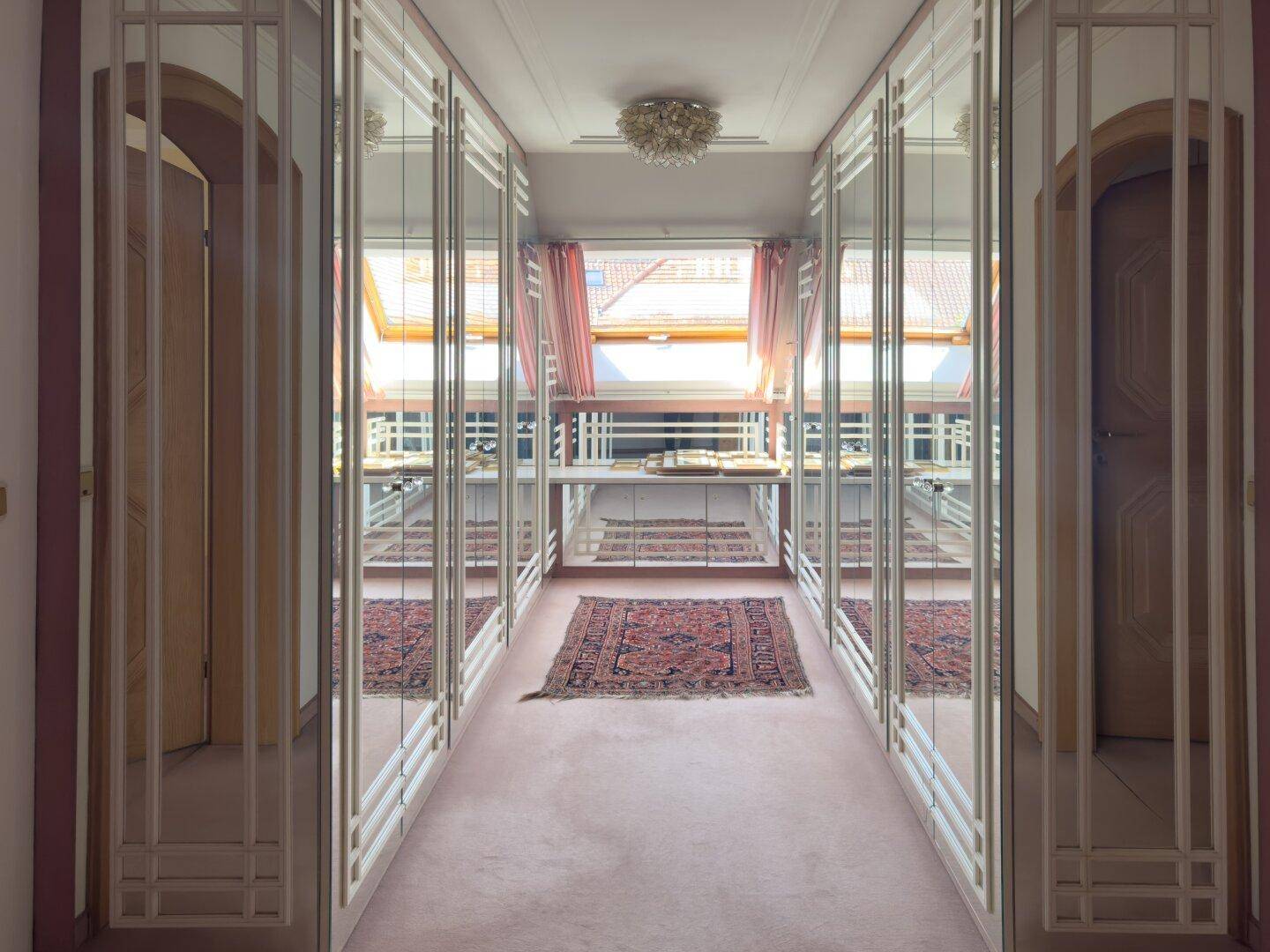 Langer Flur mit Spiegelschränken, Teppichboden und Dachfenster.