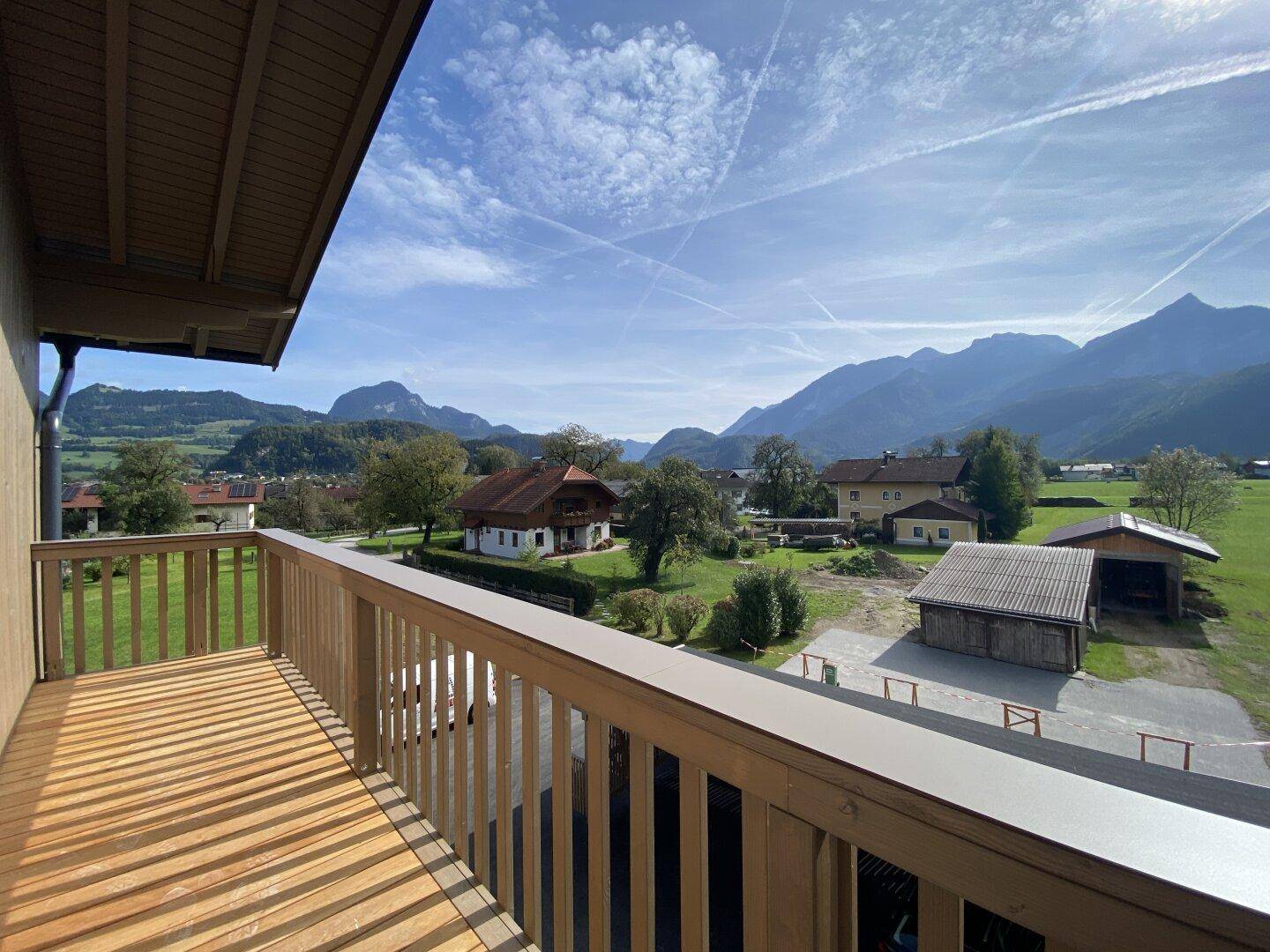 Geräumiger Holzbalkon mit atemberaubendem Blick auf die umliegende Berglandschaft und grüne Felder.