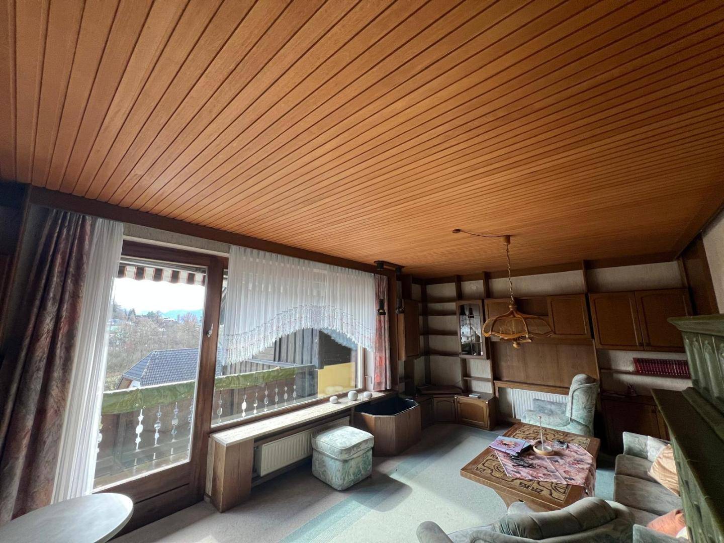 Wohnzimmer mit Holzdecken, Einbauschränken und Zugang zu einem Balkon mit Aussicht.