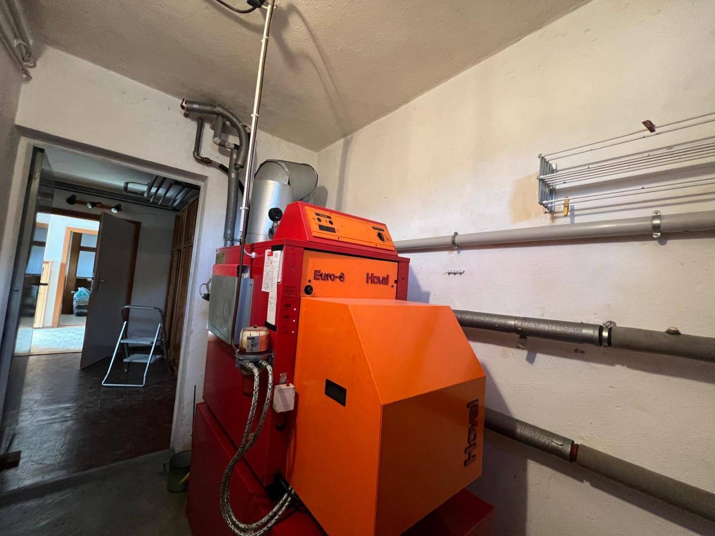 Heizungsraum im Keller mit einer großen orangefarbenen Hoval Euro-3 Heizungsanlage.