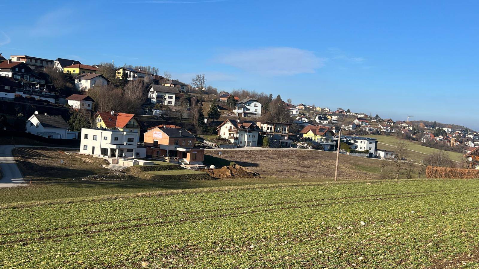 Häuser am Hang mit Blick auf die umliegende Bebauung und grüne Felder im Vordergrund.