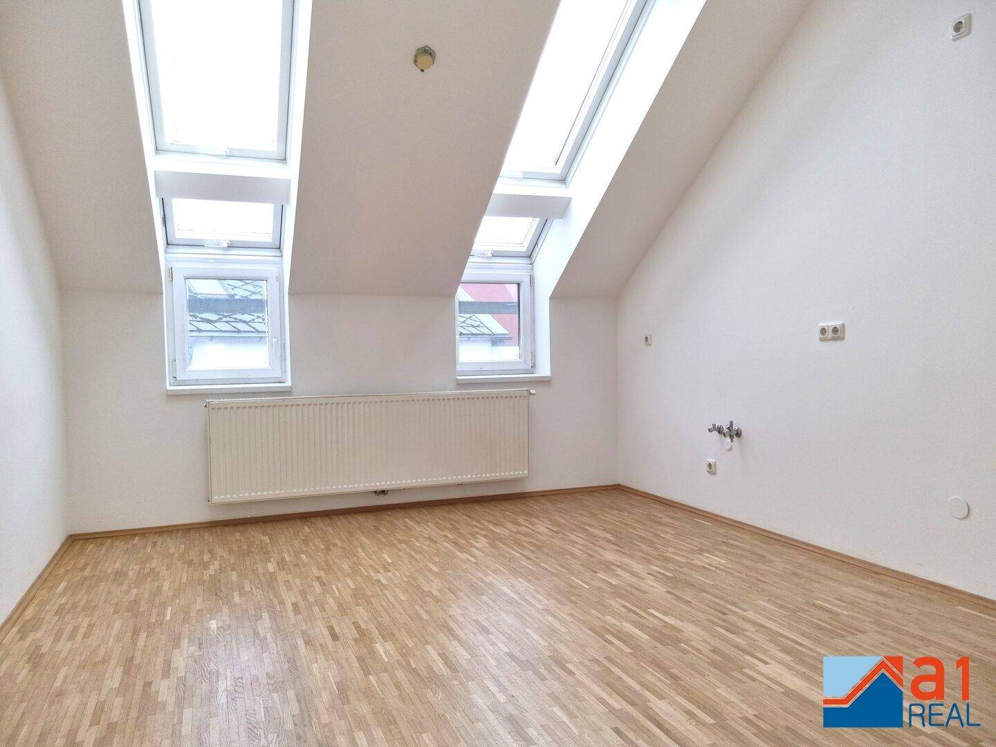 Heller Dachbodenraum mit mehreren Dachfenstern und Holzboden, bietet viel Tageslicht.