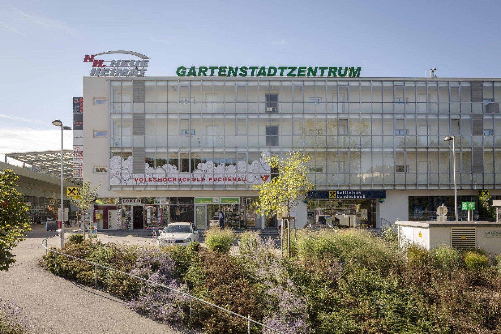Fassade des Gartencenter-Gebäudes mit großen Fenstern und Beschriftungen der Geschäfte.