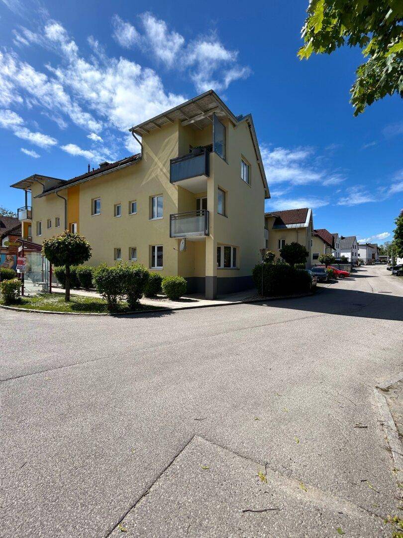 Mehrfamilienhaus mit gelber Fassade und Balkonen an einer Straßenecke gelegen.