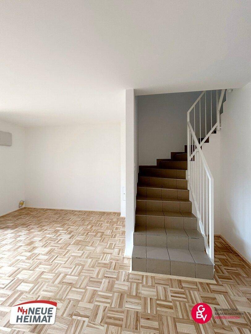 Heller Wohnbereich mit Parkettboden und Treppe zum Obergeschoss, bietet viel Raum.