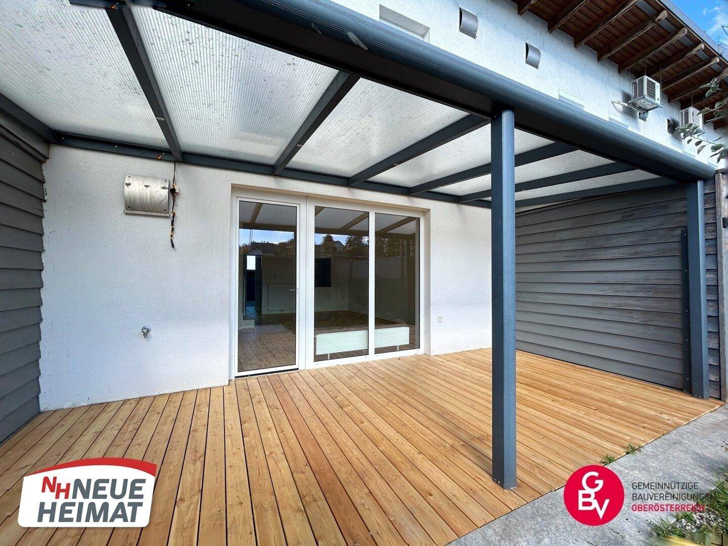 Geräumige überdachte Holzterrasse mit Blick auf den Garten, ideal für Mahlzeiten im Freien.