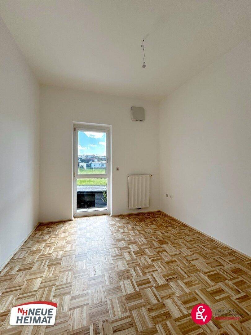 Helles Zimmer mit Parkettboden und Zugang zu einem Außenbereich, ideal für ein Schlafzimmer.