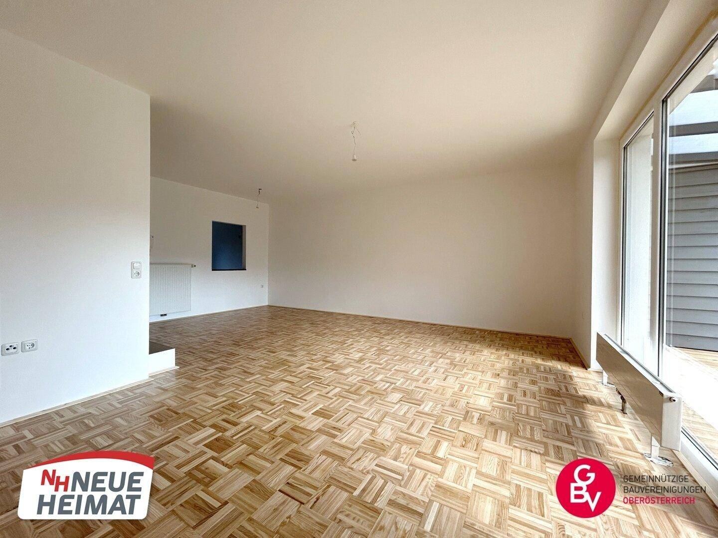 Geräumiges, leeres Wohnzimmer mit Parkettboden und großen Fenstern, bereit zur individuellen Gestaltung.